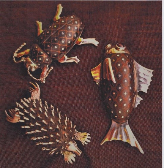 Three sterling silver brooches have been coloured in golds and deep browns. One is a beetle, another a fish, and the third is an echidna.
